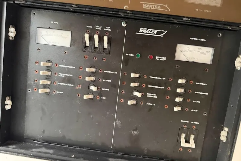 Slide: The Image of Electrical control panel of a 2002 Boston Whaler 290 Outrage boat, featuring various switches and meters. - 44