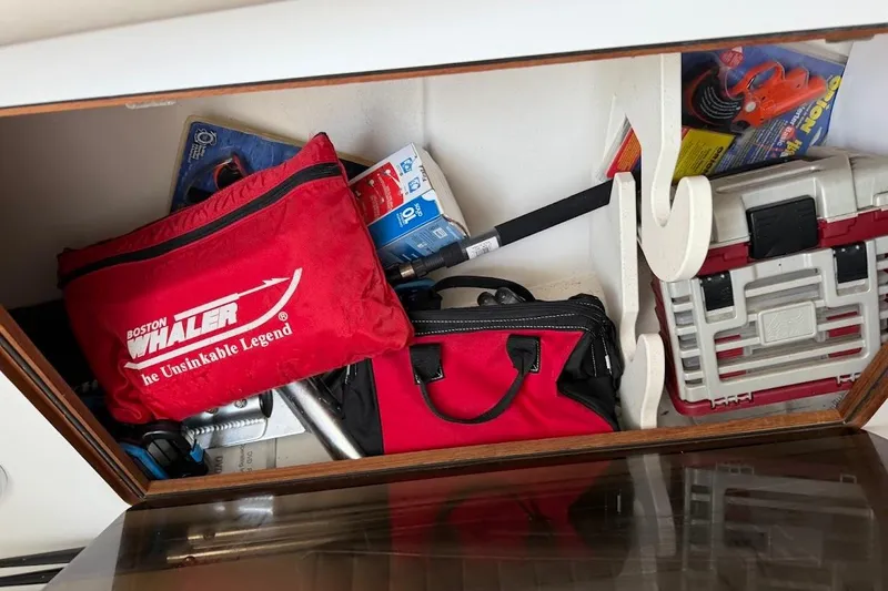 Slide: The Image of Storage compartment on a 2002 Boston Whaler 290 Outrage, featuring red bags and tools. - 45