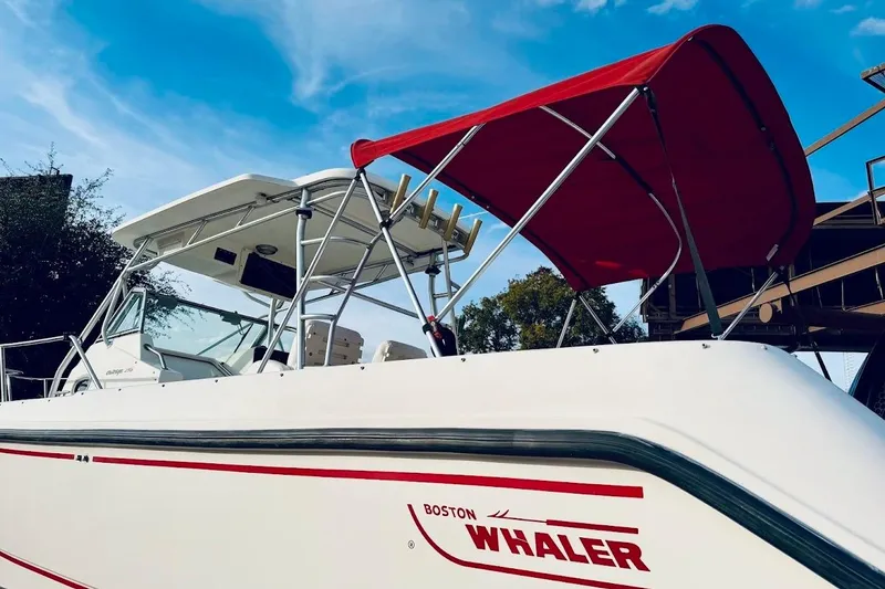 Slide: The Image of 2002 Boston Whaler 290 Outrage boat with red canopy under blue sky. - 5