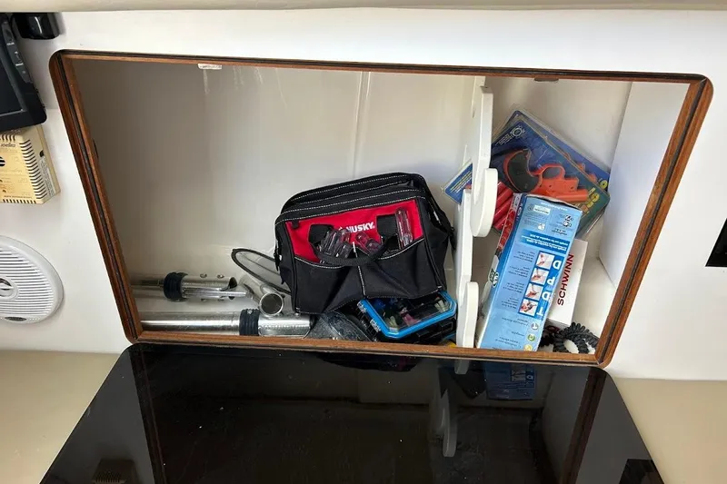 Slide: The Image of Storage compartment on a 2002 Boston Whaler 290 Outrage with tools and accessories. - 61