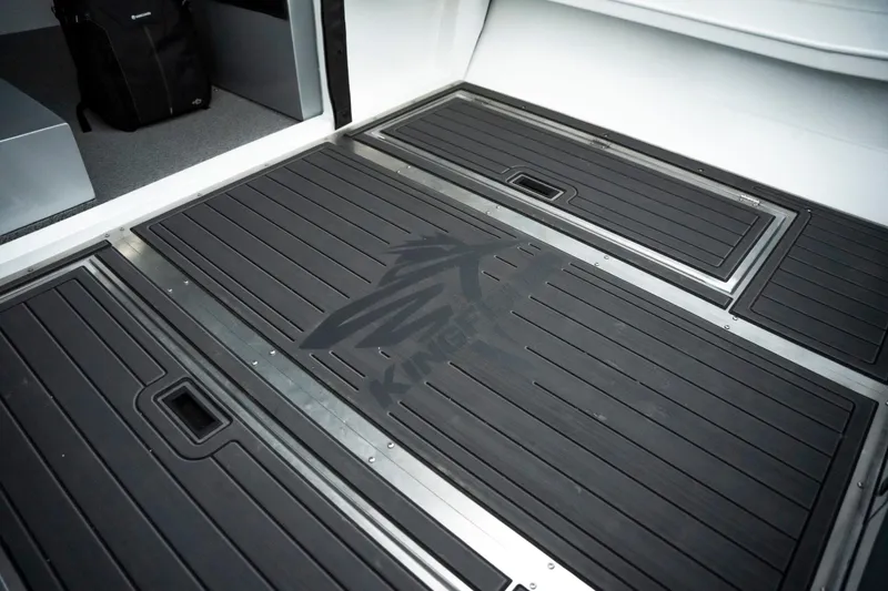 Slide: The Image of 2026 KingFisher 23 XAC boat interior with sleek black flooring and storage compartments. - 12