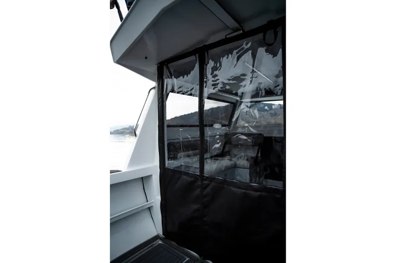 Slide: The Image of 2026 KingFisher 23 XAC boat interior with clear enclosure, scenic water view. - 13