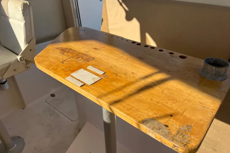 Slide: The Image of Wooden table on a 2005 Shamrock 270 Mackinaw boat, with sunlight and chair visible. - 18