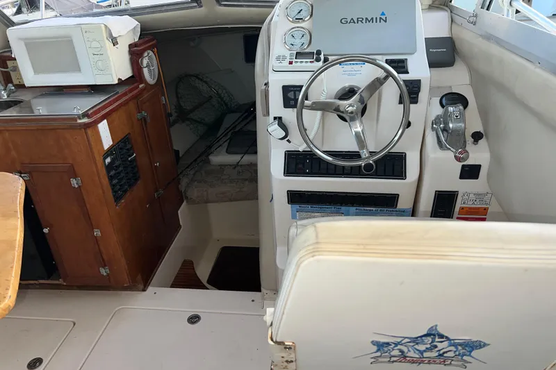 Slide: The Image of 2005 Shamrock 270 Mackinaw boat interior with steering wheel, Garmin GPS, and wooden cabinetry. - 5