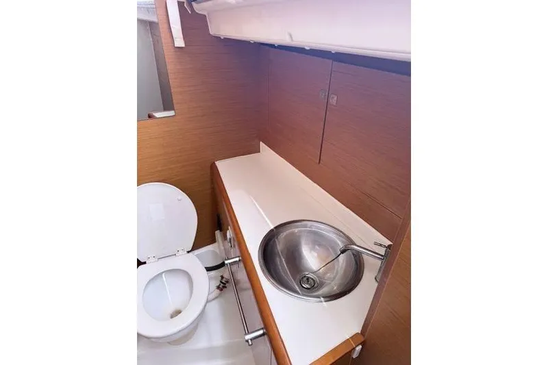 Slide: The Image of 2018 Jeanneau Sun Odyssey 419 bathroom with sink and toilet, featuring wood paneling. - 12