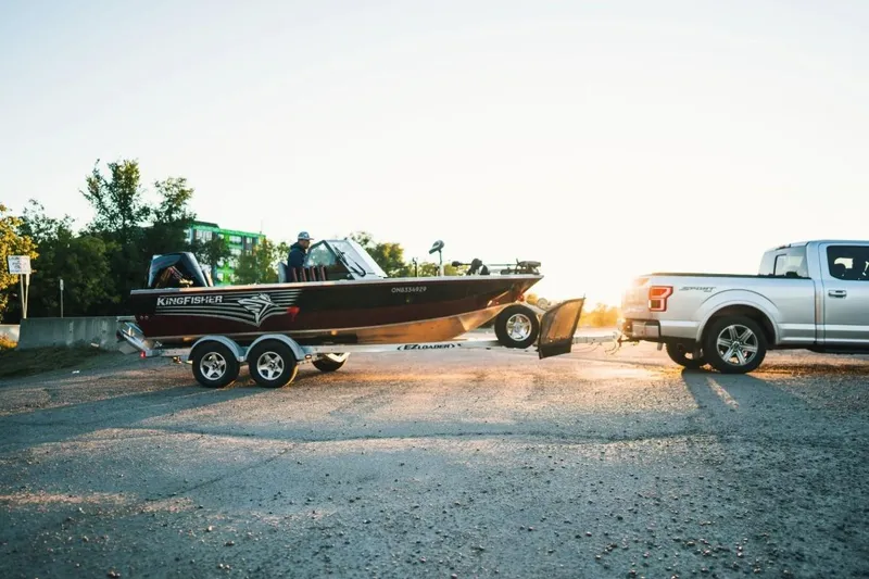 Slide: The Image of Silver truck towing a 2026 KingFisher 1925 Arrow Sport boat at sunset. - 4