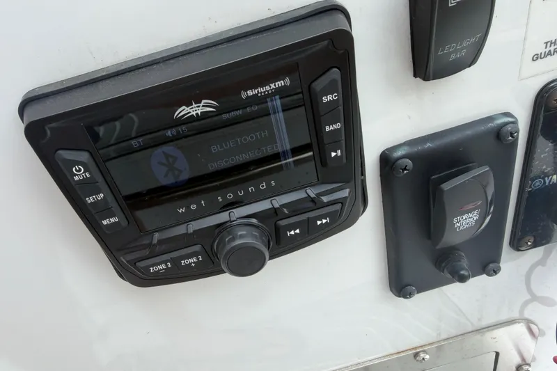 Slide: The Image of 2022 Xpress H20B Bay boat control panel with Bluetooth audio system and light switches. - 15