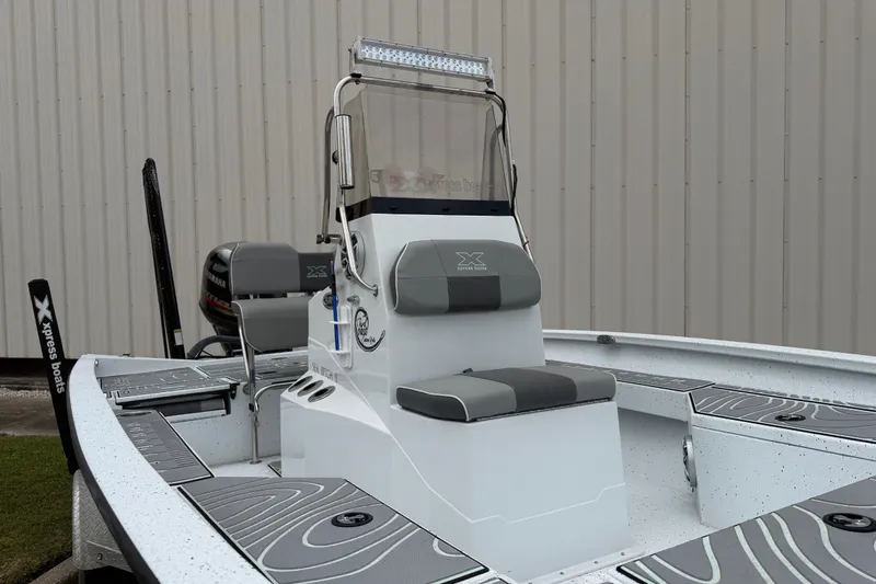 Slide: The Image of 2022 Xpress H20B Bay boat with seating and console, parked near a building. - 7