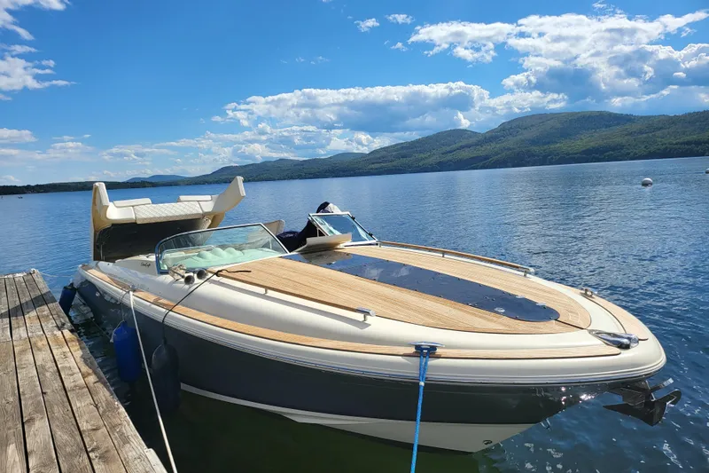 Slide: The Image of 2014 Chris Craft Corsair 34 docked on a serene lake with scenic mountain views. - 2