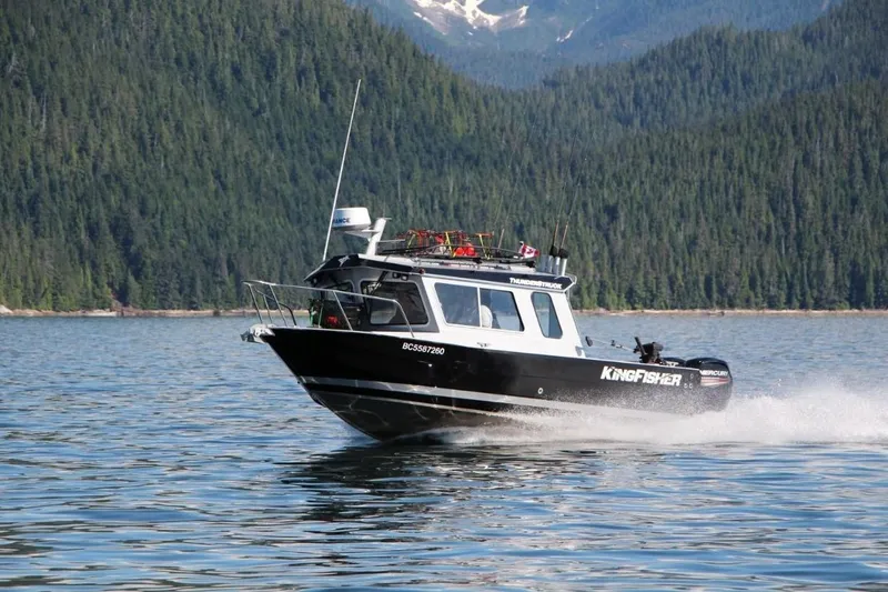 The Image of 2026 KingFisher 2325 Coastal Express boat cruising on scenic lake with forested mountains. - 1