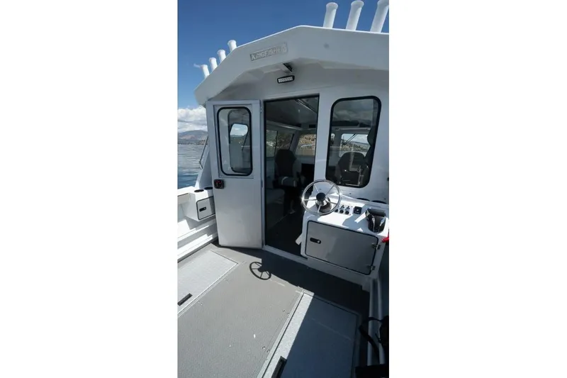 Slide: The Image of 2026 KingFisher 2325 Coastal Express boat interior with steering wheel and open cabin door. - 10