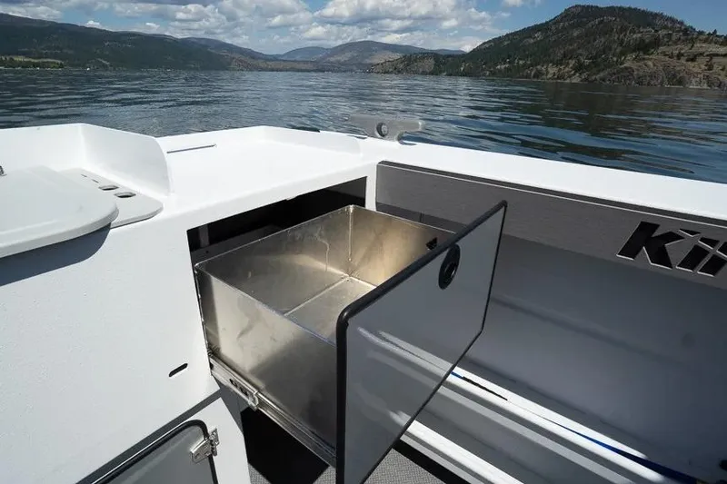 Slide: The Image of Open storage compartment on 2026 KingFisher 2325 Coastal Express boat, scenic lake view. - 11