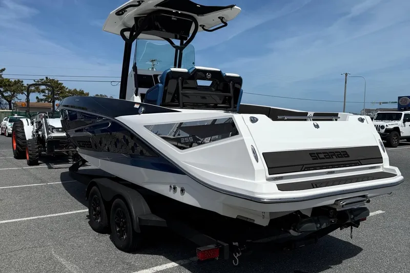 Slide: The Image of 2021 Scarab 255 Open ID boat on trailer in parking lot under clear sky. - 6