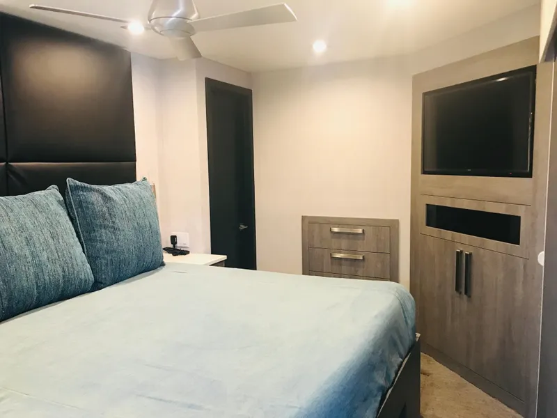 Slide: The Image of Modern RV bedroom with blue bedding, built-in TV, and ceiling fan in Adonia Adonis Trip 3, 2018. - 2
