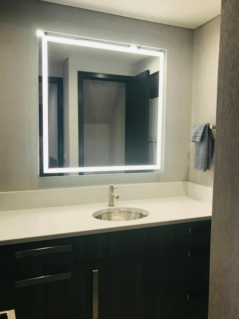 Slide: The Image of Modern bathroom with illuminated mirror, sleek sink, and dark cabinetry. Adonia Adonis Trip 3, 2018. - 3