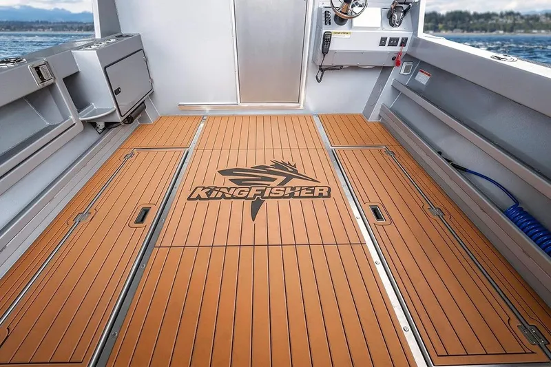 Slide: The Image of 2026 KingFisher 3225 GFX Offshore boat deck with logo, featuring wood-like flooring. - 34