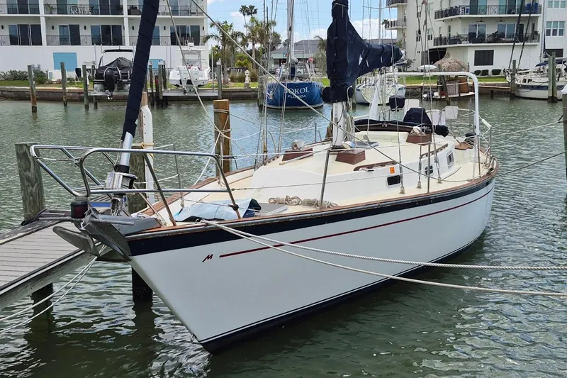 The Image of 1987 Morgan 384 sailboat docked in a marina, surrounded by water and buildings. - 0