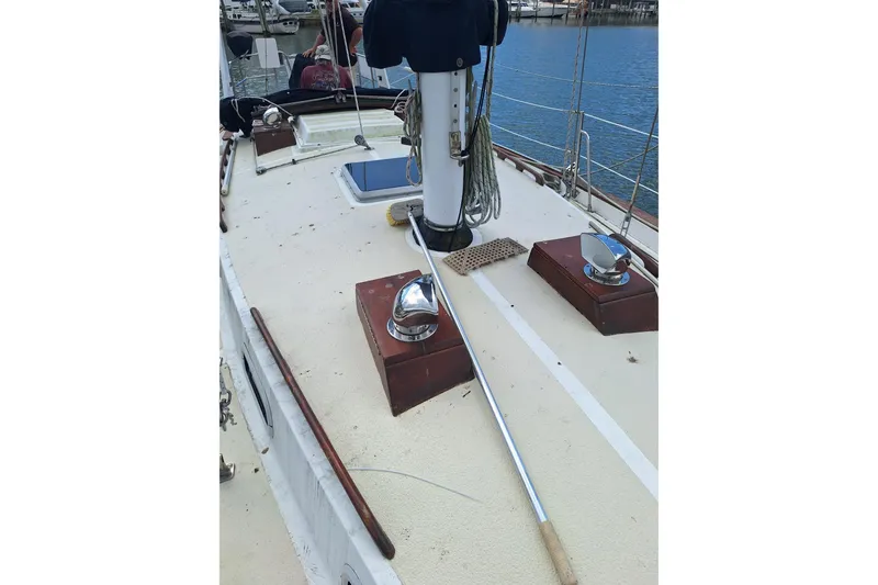 Slide: The Image of 1987 Morgan 384 sailboat deck with winches and mast, docked by the water. - 10