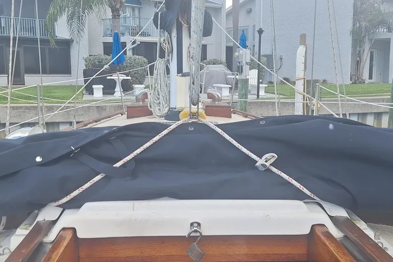 Slide: The Image of 1987 Morgan 384 sailboat docked, covered with tarp, residential background. - 14