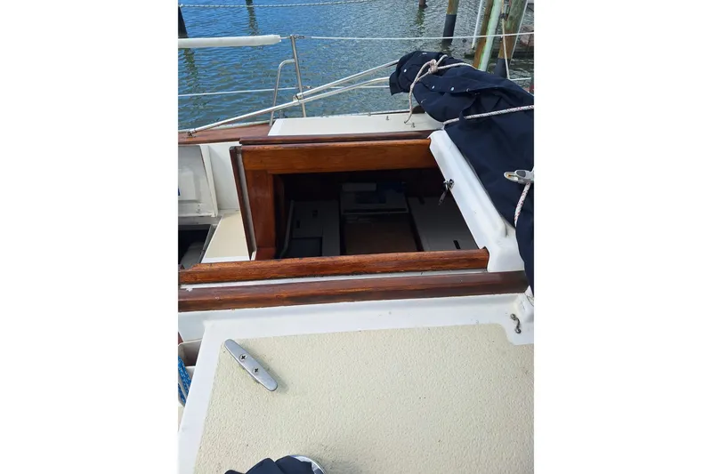 Slide: The Image of 1987 Morgan 384 sailboat cockpit with open hatch, docked by the water. - 17