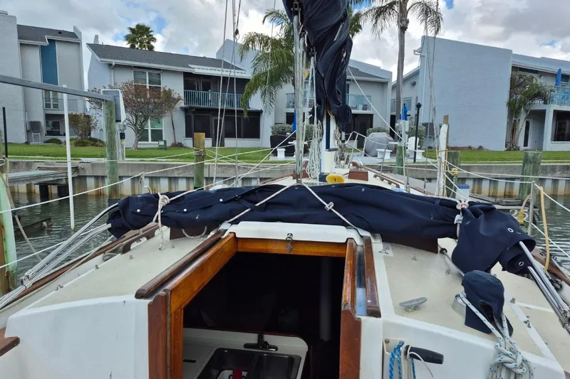 Slide: The Image of 1987 Morgan 384 sailboat docked near waterfront homes, featuring covered sails and rigging. - 18