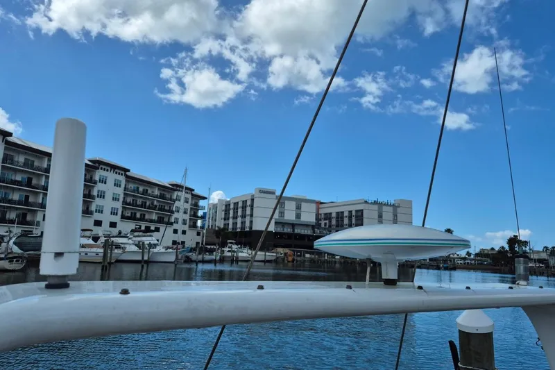 Slide: The Image of Sailboat docked at marina with buildings in background, clear blue sky above. - 20