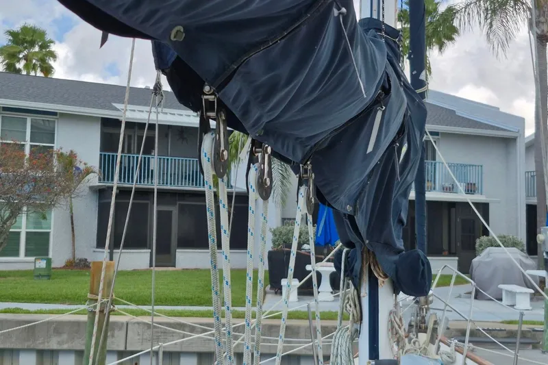 Slide: The Image of 1987 Morgan 384 sailboat with covered mainsail, docked near residential buildings. - 21