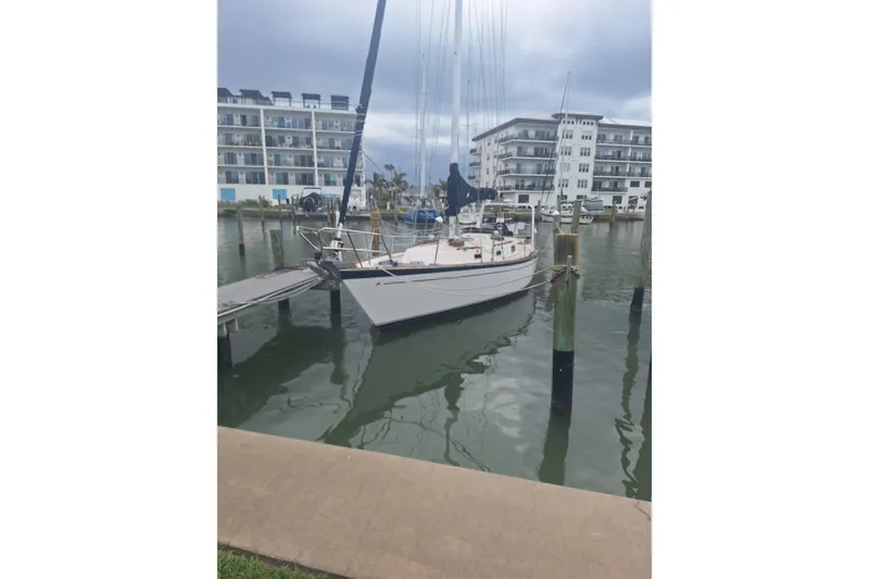 Slide: The Image of 1987 Morgan 384 sailboat docked in a marina with modern buildings in the background. - 40