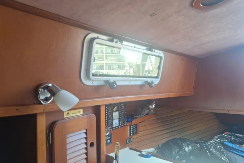 Slide: The Image of Interior of a 1987 Morgan 384 sailboat cabin with wooden paneling and a small window. - 46