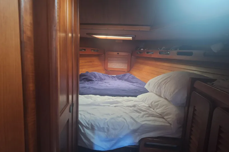 Slide: The Image of Cozy cabin interior of a 1987 Morgan 384 sailboat with wooden paneling and bedding. - 47