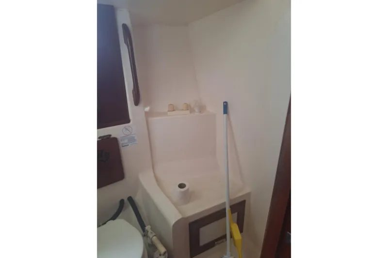 Slide: The Image of 1987 Morgan 384 yacht bathroom with toilet, cleaning supplies, and storage area. - 52