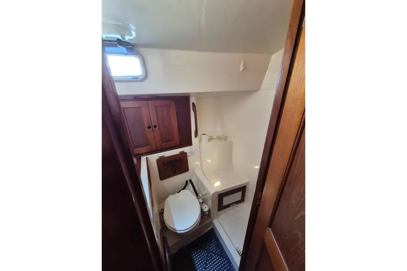 Slide: The Image of 1987 Morgan 384 yacht bathroom with wooden cabinets and a porthole window. - 57