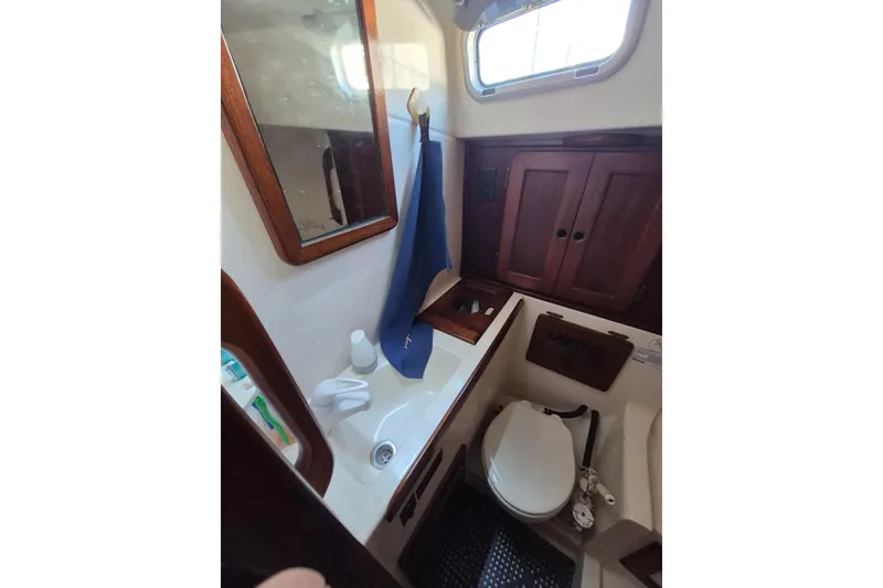 Slide: The Image of 1987 Morgan 384 yacht bathroom with wooden cabinets, mirror, and compact toilet. - 58