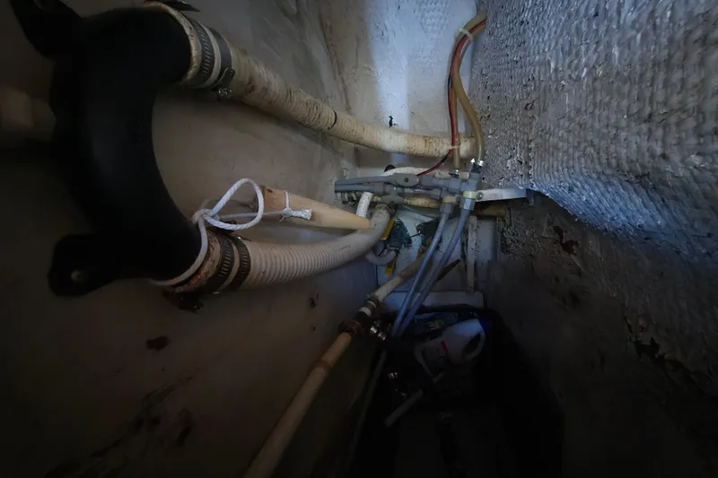 Slide: The Image of 1987 Morgan 384 boat interior showing plumbing and hoses in a confined space. - 59