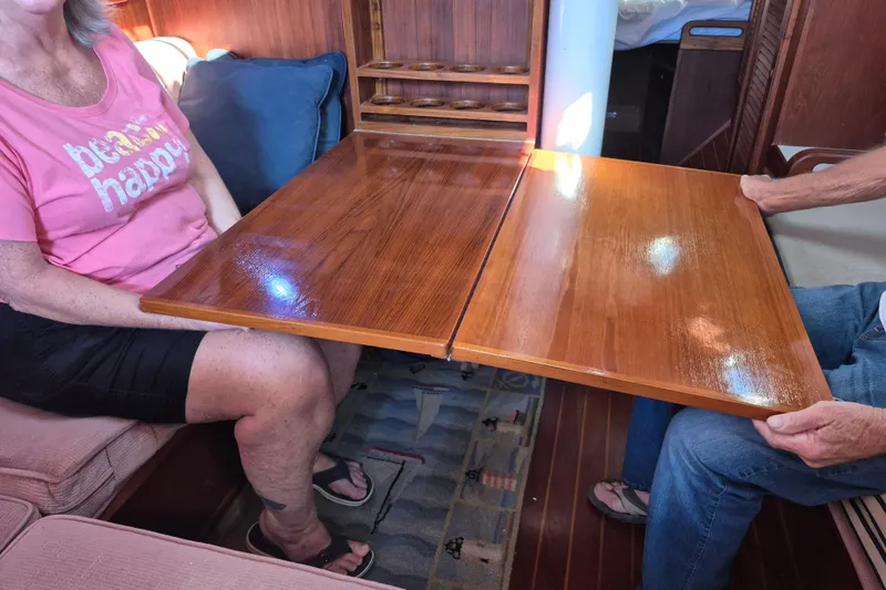 Slide: The Image of Interior of 1987 Morgan 384 sailboat with foldable wooden table and seating area. - 62