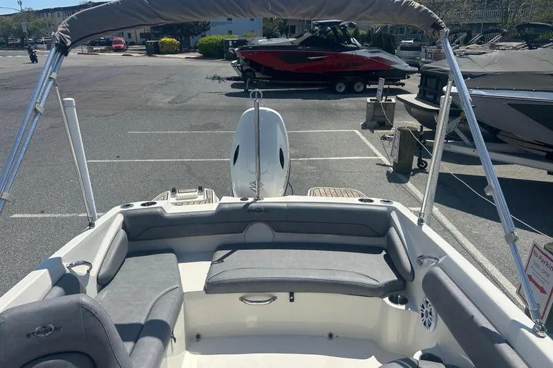 Slide: The Image of 2022 Stingray 182 SC boat interior with seating and canopy in a parking lot. - 15