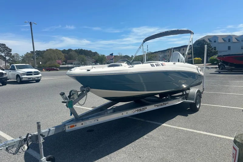 Slide: The Image of 2022 Stingray 182 SC boat on trailer in parking lot under clear blue sky. - 4