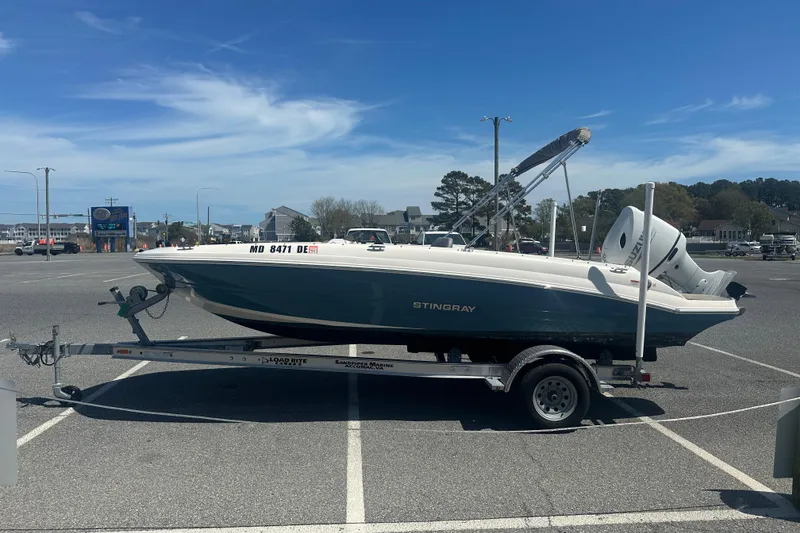 Slide: The Image of 2022 Stingray 182 SC boat on trailer in parking lot under clear blue sky. - 5