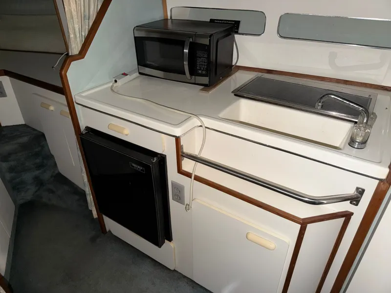 Slide: The Image of 1989 Sea Ray 300 Sundancer kitchen area with microwave and sink. - 8
