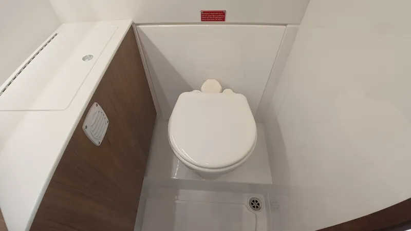 Slide: The Image of The image shows a clean, modern boat toilet with wood paneling. - 36