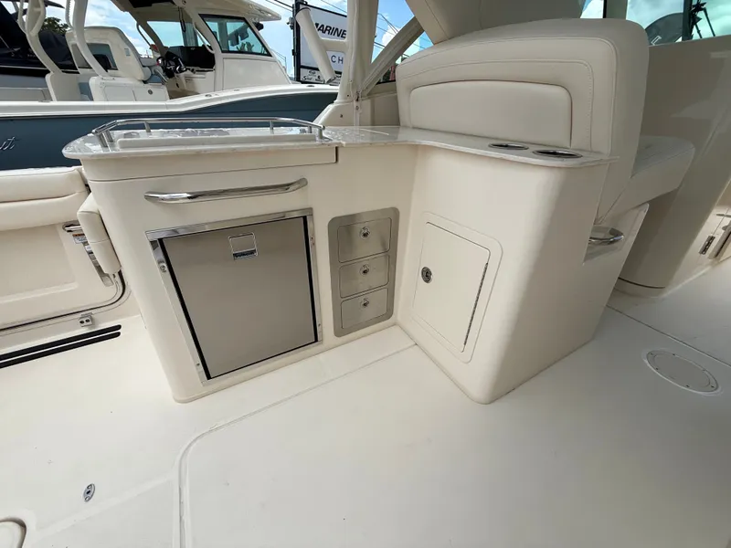Slide: The Image of The 2027 Grady-White Freedom 325 features a sleek, cream-colored onboard kitchen with storage and a refrigerator. - 15