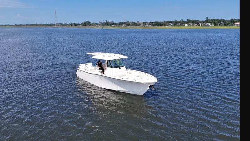 Slide: The Image of A 2027 Grady-White Canyon 306 cruising on calm waters with a clear sky in the background. - 26