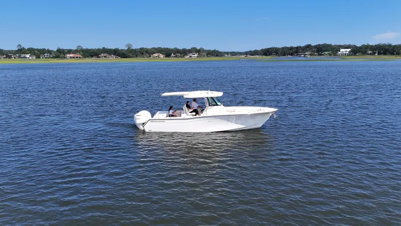Slide: The Image of A 2027 Grady-White Canyon 306 boat on calm water with a green shoreline in the background. - 25