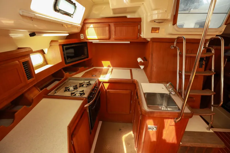 Slide: The Image of Interior of 1997 Hunter Passage 42 sailboat kitchen with wooden cabinetry and stainless steel sink. - 13