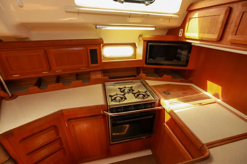 Slide: The Image of 1997 Hunter Passage 42 yacht kitchen with wooden cabinetry, stove, and microwave. - 14