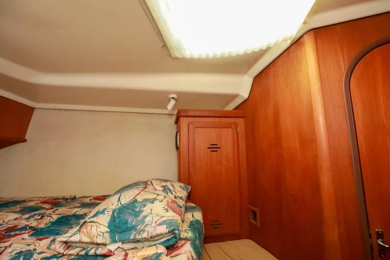 Slide: The Image of Cozy cabin interior of 1997 Hunter Passage 42 sailboat with wooden paneling and patterned bedding. - 32