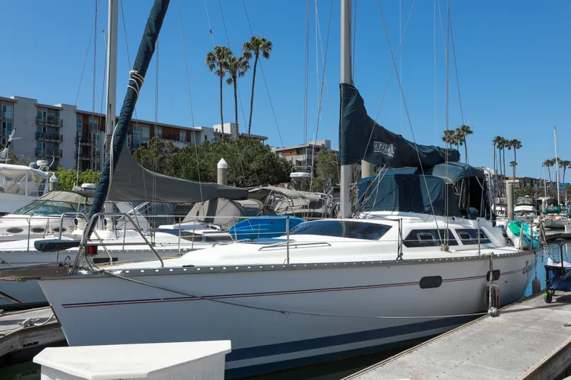 Slide: The Image of 1997 Hunter Passage 42 sailboat docked in a marina with palm trees and buildings. - 4