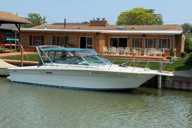 The Image of 1994 Sea Ray 310 Amberjack boat docked by a waterfront house. - 0