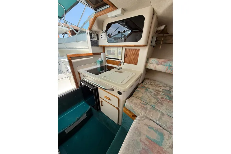 Slide: The Image of 1994 Sea Ray 310 Amberjack cabin interior with kitchenette, sink, and seating area. - 13
