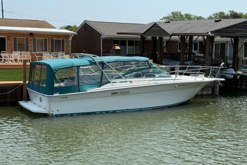 Slide: The Image of 1994 Sea Ray 310 Amberjack boat docked by waterfront homes. - 2
